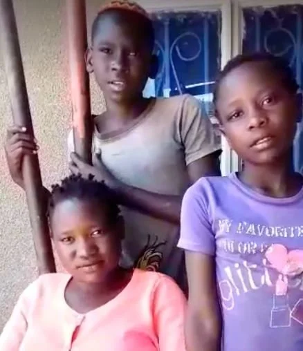Three children standing together by a doorway